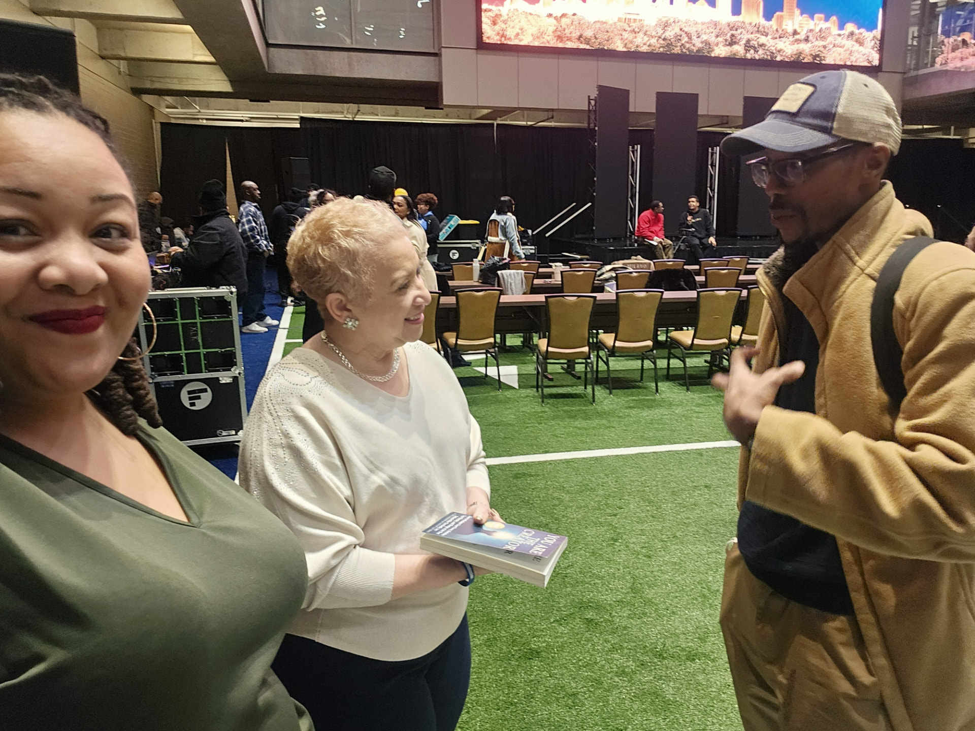 A reader holding a copy of You Are the Creator on an event floor with Madison and Geo Dixon nearby